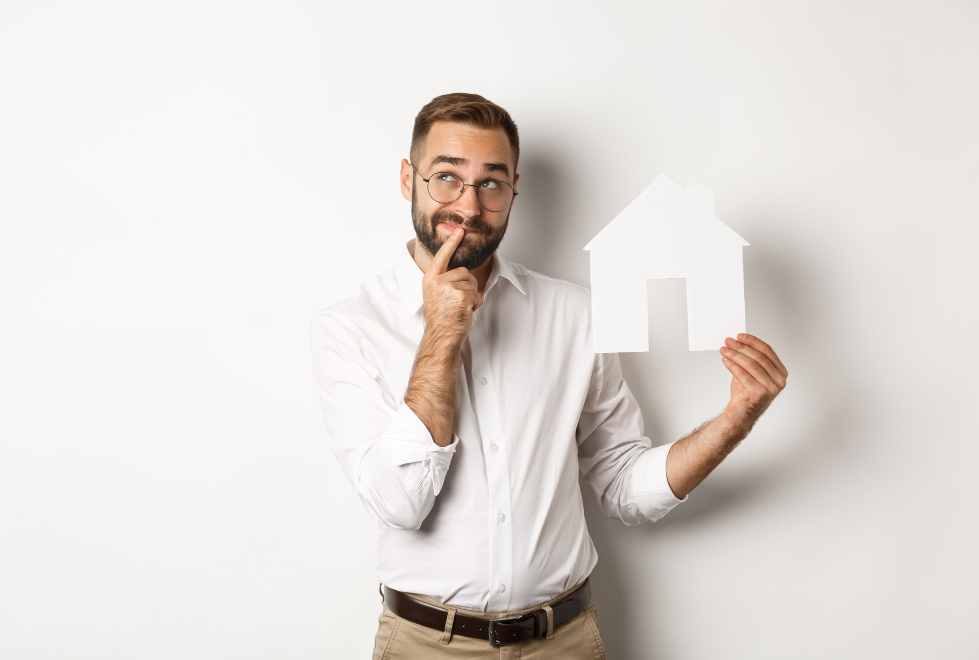 homme tient une maison en carton dans la main