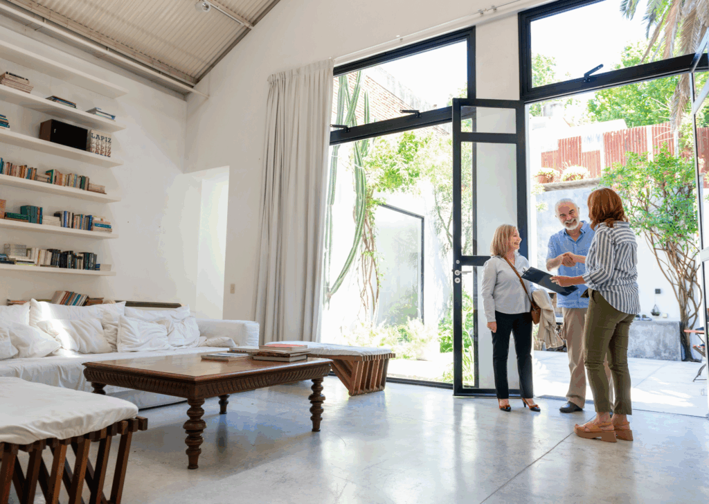 Un couple visite une maison lumineuse et moderne avec une agente immobilière, discutant d'une potentielle acquisition immobilière dans un cadre convivial.