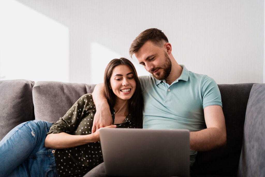 Un homme et une femme assis sur le canapé avec un ordinateur portable