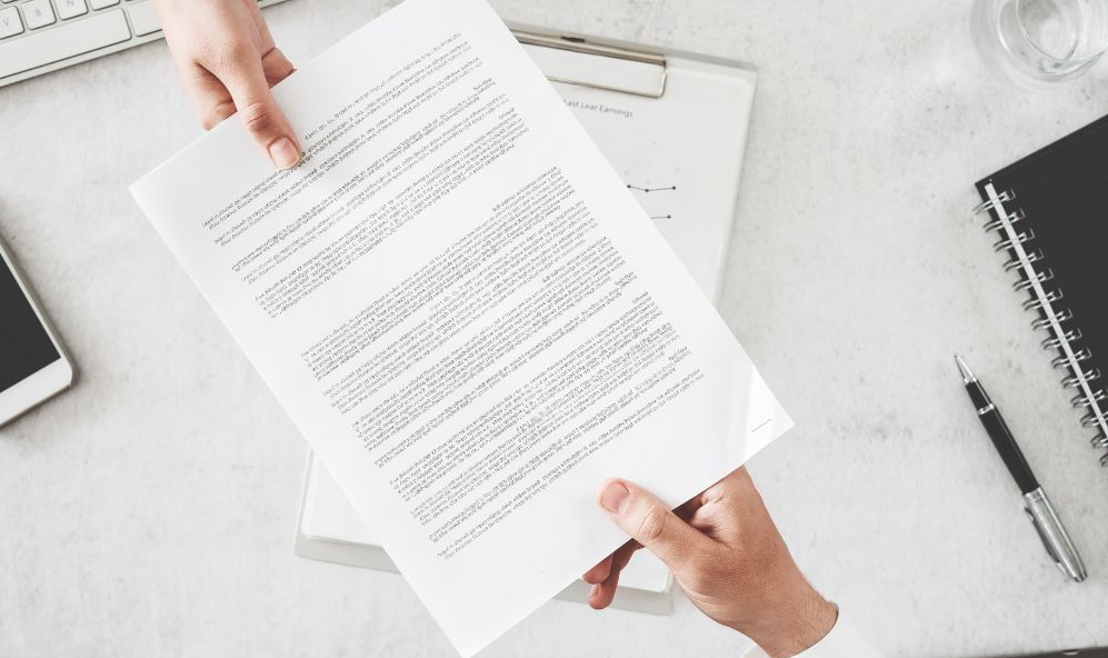 On aperçoit un main qui tend un document à une autre main