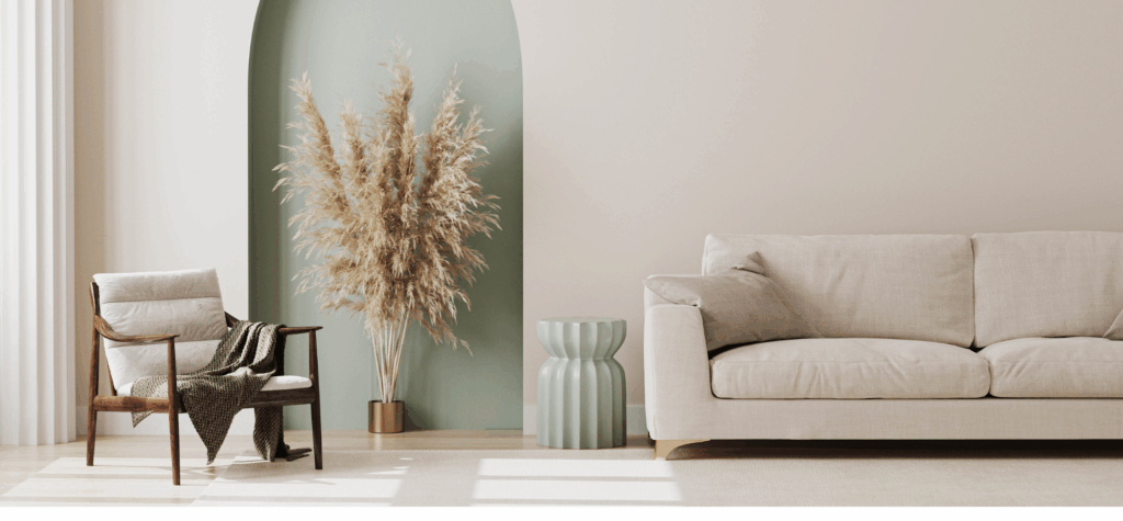 On aperçois un canapé avec une petite décoration à coté ainsi qu'un pouf, l'ambiance est assez épuré dans les couleurs beige et blanche