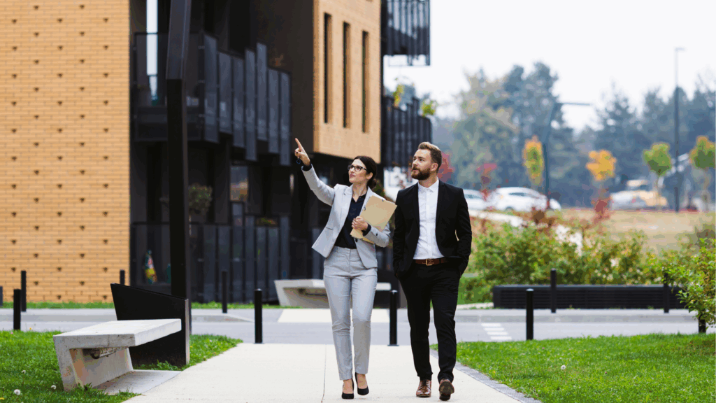 On aperçoit une agent immobilière se promenant avec un homme vêtu d'un costard