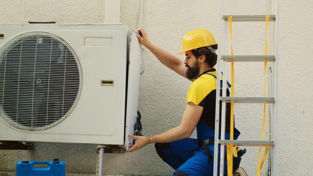 un technicien installe une climatisation sur un bâtiment