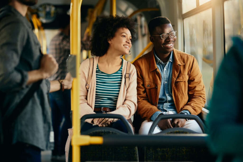 Un couple noir heureux regardant par la fenêtre en faisant la navette en bus.